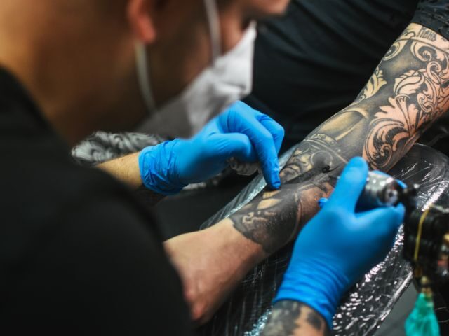 Large colour tattoo being worked on by two artists