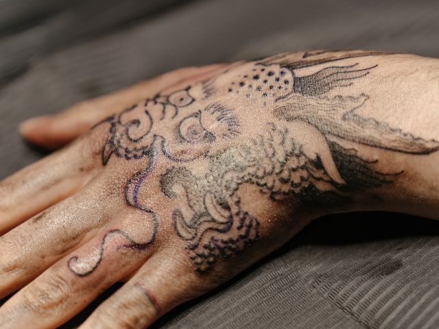 Fine line dotwork tattoo of a bird on a hand